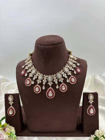 A beautiful Moissanite and AD necklace set with green or red Meenakari detailing. The combination of oval and teardrop stones gives this piece a unique and luxurious appeal.