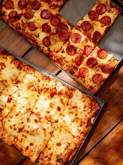 A top-down view of our Pizza Romana, one with pepperoni and one classic cheese, showing the crispy, golden crust.