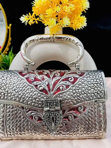 This silver box clutch features a different style of craftsmanship, with a dotted texture and red enamel accents. It’s a modern take on a traditional design, perfect for the contemporary woman.