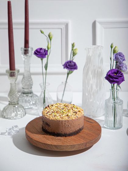 The Chocolate Pistachio Ice Cream Cake, a nutty and chocolatey creation, sits elegantly on a wooden platter. A simple yet irresistible flavour combination.