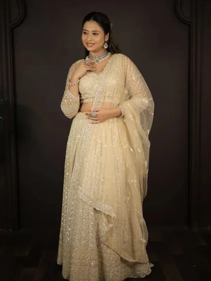 A full-length shot of the model in the elegant golden-beige lehenga.