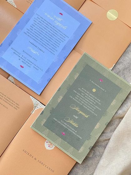 Minimalist wedding invitations for a modern, chic celebration. The design uses a simple color palette of olive green and sky blue on the event cards, enclosed in a warm tan envelope.