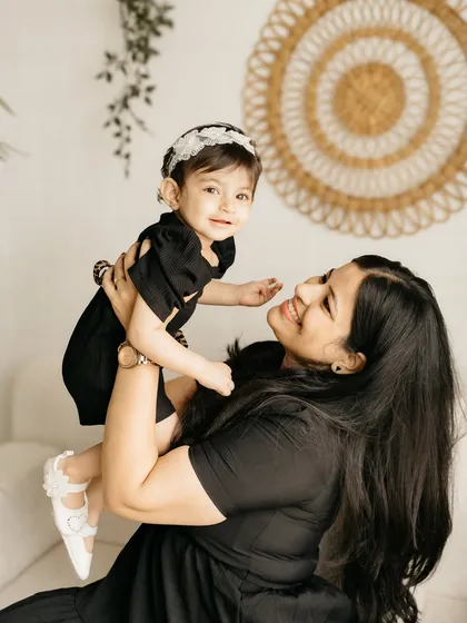 A mother lifting her daughter in the air, both sharing a look of pure joy.