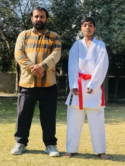 A student stands proudly with Sensei Amresh Singh after his belt test. Earning a new belt is a significant milestone in a karateka's journey.