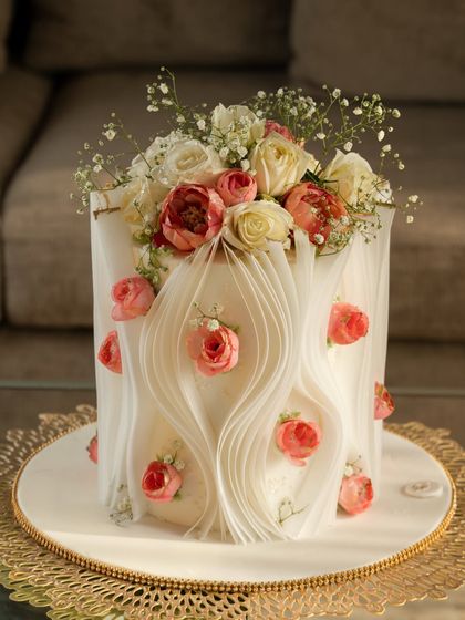 For this design, I created gentle waves with the wafer paper, embedding small pink roses within the folds. The cake is topped with a fresh bouquet of baby's breath and roses, blending edible art with natural beauty.