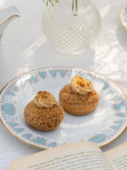 A close-up of our fluffy and creamy Choux Pastries. These light-as-air pastries are filled with a Biscoff cream and have a crunchy craquelin top, offering a delightful texture and flavour.
