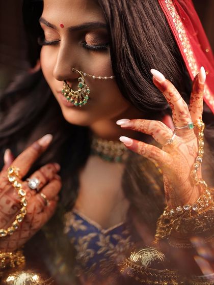 A detailed bridal portrait that glorifies the artistry. Notice the soft smokey eye, the perfectly placed bindi, and the heirloom nath, all coming together to create magic.