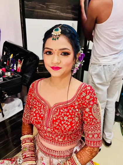 An in-the-making shot, showing the bride getting her makeup done before the final look is complete.