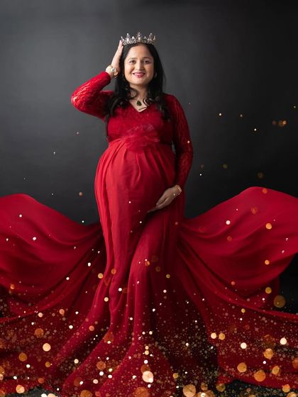 A queen celebrating her new beginning. This portrait in a stunning red gown with a sparkling train and a crown is the definition of regal maternity glamour.