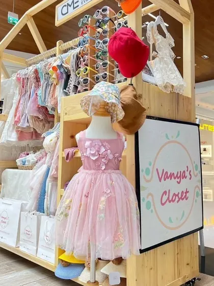 Another view of a custom wooden kiosk for a kids' fashion brand, 'Vanya's Closet'. The mobile design includes clothing racks and a prominent space for branding, making it a versatile solution for mall exhibitions.