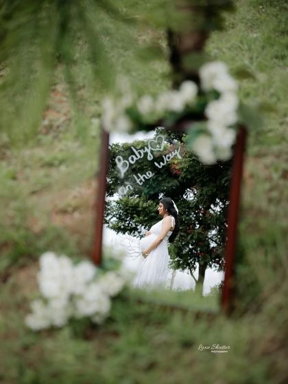Another creative use of a mirror in an outdoor setting. The reflection captures a beautiful portrait with a fun, handwritten "Baby on the way" message.