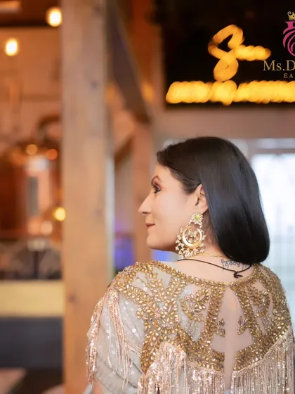 A side profile showing the intricate details of the blouse and the beautiful makeup that completes the look.