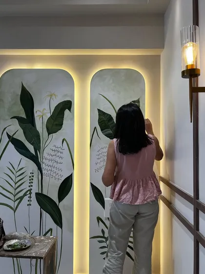 A final look at a botanical mural painted on two arched panels in a residential hallway. The backlighting enhances the artwork, making the lush green leaves and delicate flowers glow.