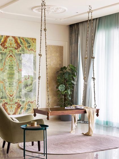 A traditional solid wood swing becomes a stunning focal point against a custom-made tile installation with a bold green marble pattern. This space is designed for relaxation, with an elegant armchair and soft rug creating a perfect corner to unwind.