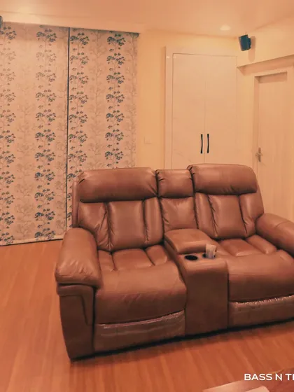 A cozy living room transformed into a home theatre with a Sonos wireless surround sound system. The compact satellite speakers and recliner create a perfect spot for Netflix nights.