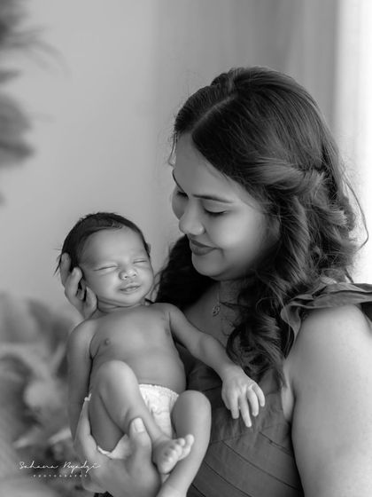 A beautiful black and white portrait of a mother and her smiling newborn. The emotion is so powerful.