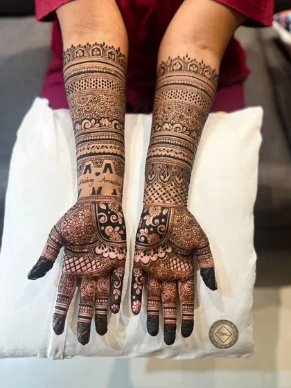 This intricate henna design extends up the forearms with multiple bands of detailed patterns. We also included the couple's initials, 'Akshay' and 'Amrutha', for a personal touch.