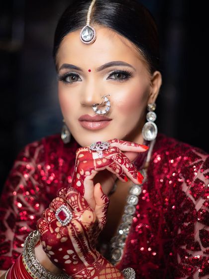 A radiant bridal portrait of a model with vitiligo. The makeup is flawless, with a focus on her bright eyes and glowing skin, complemented by a sequined red lehenga and diamond jewelry.