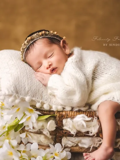 A beautiful newborn girl, crowned with a delicate headband, sleeps peacefully among fresh white flowers. This setup is perfect for creating a light, airy, and angelic portrait.