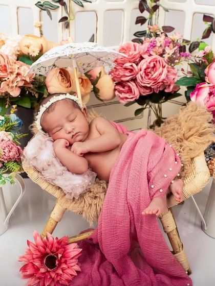 A delicate and detailed newborn setup. The miniature umbrella, lace details, and floral arrangements create a sweet, picturesque scene.