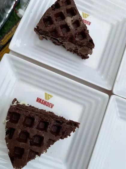 A slice of our decadent chocolate waffle, served on a custom Vashdev plate. We pay attention to every detail, including our branding and presentation.
