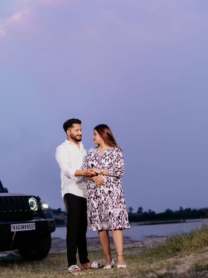 A modern maternity portrait of a couple standing by their car against a dusky sky. This shot has a casual, adventurous feel, perfect for couples who want something different.