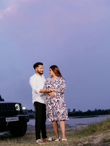 A modern maternity portrait of a couple standing by their car against a dusky sky. This shot has a casual, adventurous feel, perfect for couples who want something different.