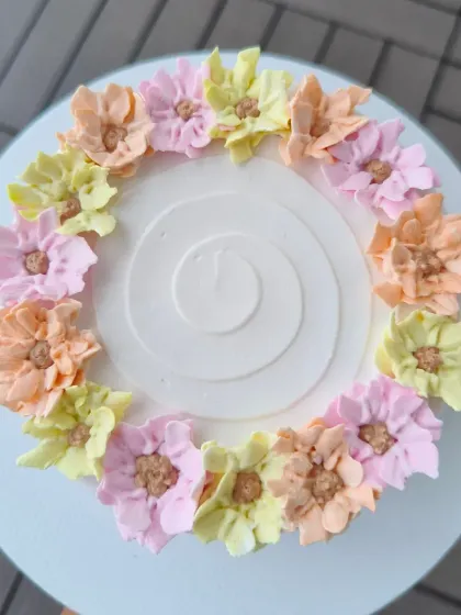 A top-down view of the floral wreath cake, showing the delicate piping work on each flower.