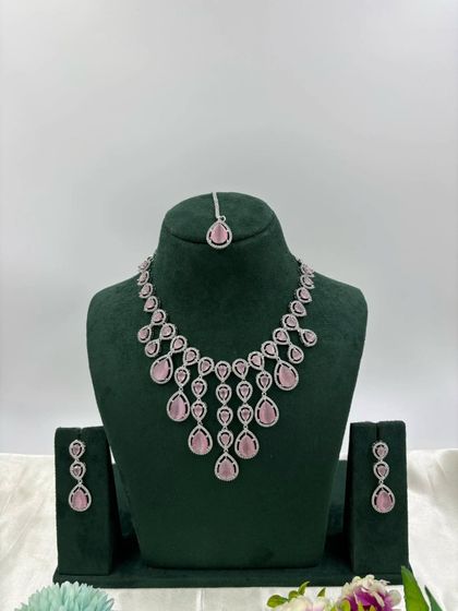 An elegant AD necklace set with a matching maang tikka. The cascading design with teardrop stones is available in green, pink, and all-white, perfect for receptions and parties.