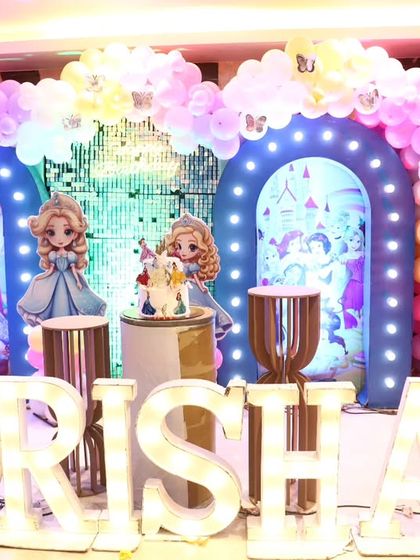 A grand princess-themed stage for Risha's 5th birthday, featuring marquee letters, multiple backdrops, and pastel balloon clouds.