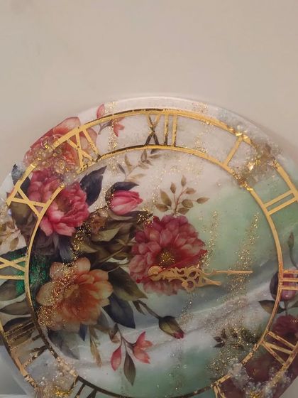 This mix-media floral clock combines decoupage techniques with resin art. The vintage floral design is enhanced with a glossy resin topcoat and gold accents, creating a beautiful and functional piece of decor.
