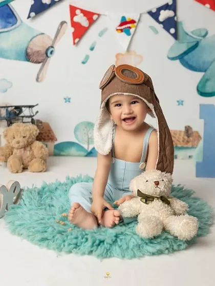 This little aviator is flying high into his second year. The complete setup with a vintage plane backdrop and 'ONE' sign made for an adventurous first birthday portrait.