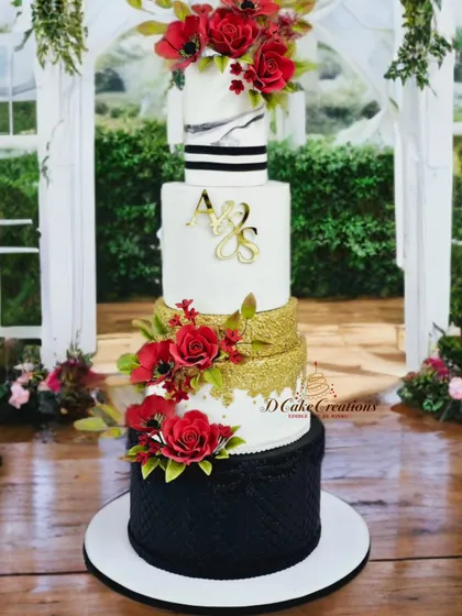 A striking five-tier wedding cake that combines multiple styles. It features a textured black base, a gold sequin tier, a marble-effect tier, and is finished with a custom monogram and beautiful handmade red sugar poppies and roses.