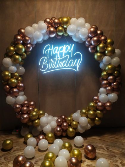 A classic and versatile circular balloon arch in white, gold, and rose gold. The bright "Happy Birthday" neon sign makes it a perfect photo backdrop for any age.