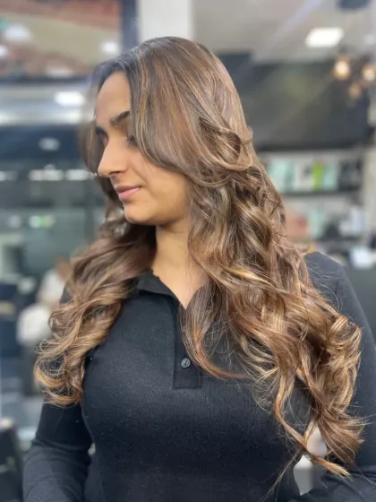 This client's long hair is styled into gorgeous, cascading curls with beautiful highlights, creating a truly glamorous and eye-catching look.