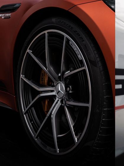 A detailed photograph of a Mercedes-AMG wheel, showcasing the intricate design of the alloy and the performance branding. This highlights the performance-oriented details that appeal to car enthusiasts.