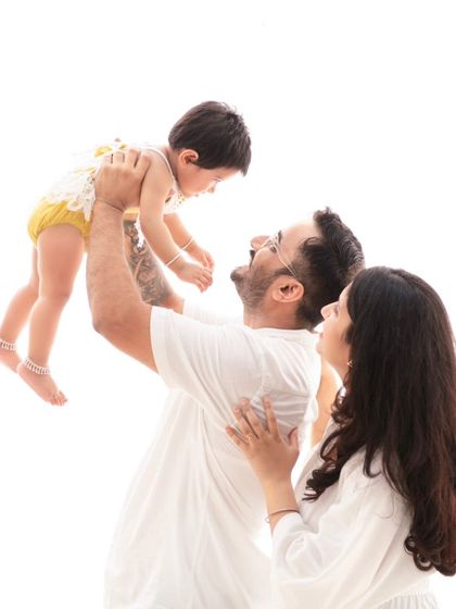 A moment of pure joy as a father lifts his daughter. The white outfits and bright background give this photo a light and airy feel.