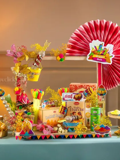 A grand and colorful Holi hamper, elaborately styled with paper fans and floral decorations.