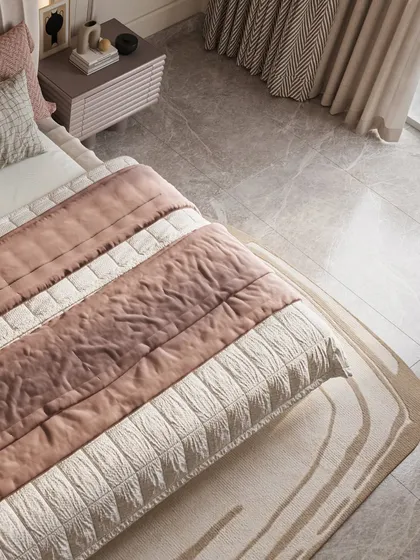 Texture plays a key role in creating a sense of comfort. This overhead shot details the layered bedding, with its mix of quilted fabrics in blush and cream, and the softly patterned rug that grounds the space.