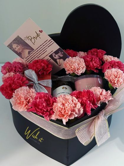 A beautiful heart-shaped box for the bride-to-be, filled with pink carnations, a scented candle, and other small luxuries. It’s a perfect gift for a bridal shower or just to show your love.