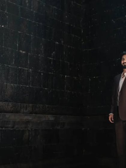 A dramatic, wide-shot pre-wedding portrait against a dark wall, creating a modern and sophisticated look.