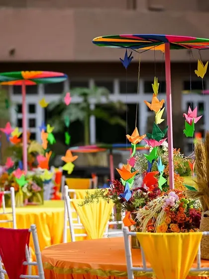 Whimsical table centerpieces with colourful pinwheels and paper cranes, adding a playful touch to the guest seating.