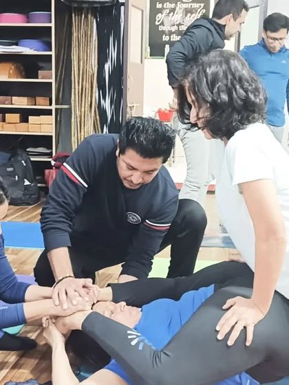 Learning the art of adjustment is a hands-on process. Students practice assisting each other in complex poses.