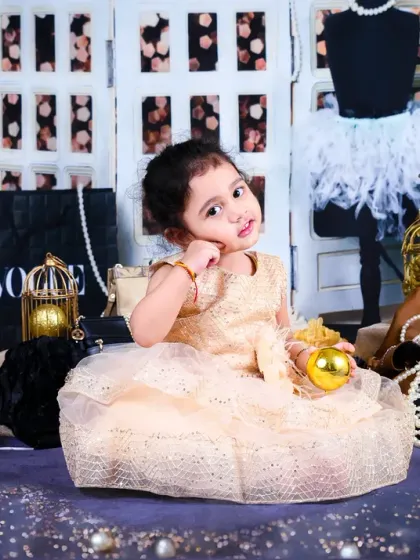 A little fashionista poses in a glamorous setup with "Vogue" bags, pearls, and a chic backdrop. A fun and stylish themed shoot.