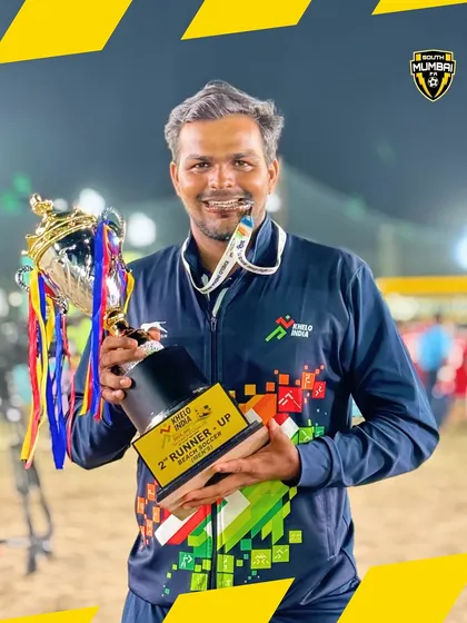 A close-up of Head Coach Suraj Jaiswal with the National Championship trophy and medal.