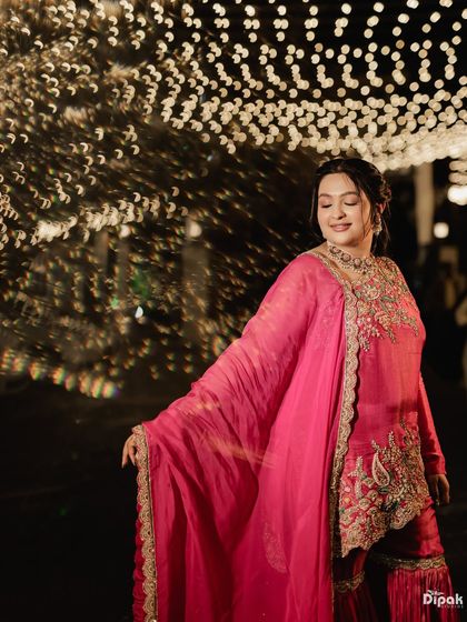 Surrounded by fairy lights, her festive glow is undeniable. This photo captures the beautiful, ethereal quality of her soft makeup for the Mata ki Chowki.