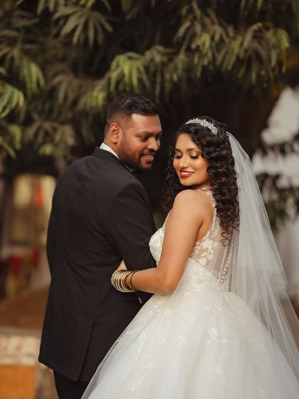 A beautiful portrait capturing the bride looking back with a smile. The focus is on her elegant gown and the loving glance she shares with her groom.