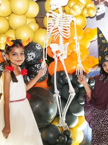 Friends celebrating together in costume. We love capturing the fun interactions between kids at themed parties, like this shot of two friends posing by the skeleton decor.