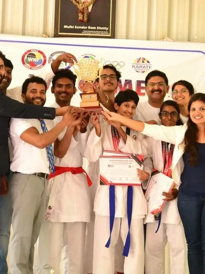The joy of teamwork and shared success. Our team celebrates a major win at our 1st District Level Karate Championship, holding up the trophy that represents all of our collective effort.