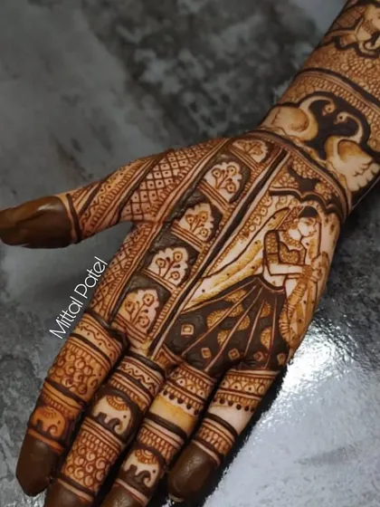 A close-up of a bride and groom portrait, showing the intimacy of the moment captured in henna. The design is framed by swans and elephants.